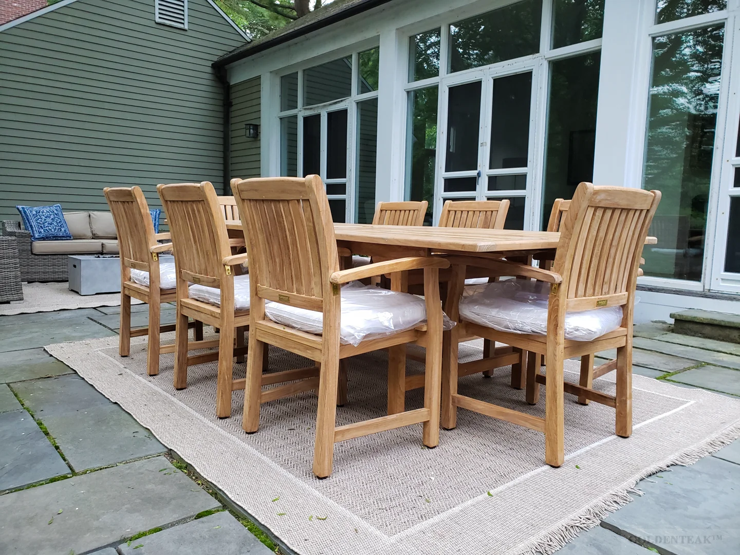 Beautifully styled teak outdoor dining set with colorful cushions, outdoor rug, string lights, and surrounding greenery - Buy teak garden furniture Beautifully styled teak outdoor dining set with colorful cushions, outdoor rug, string lights, and surrounding greenery - Buy teak garden furniture