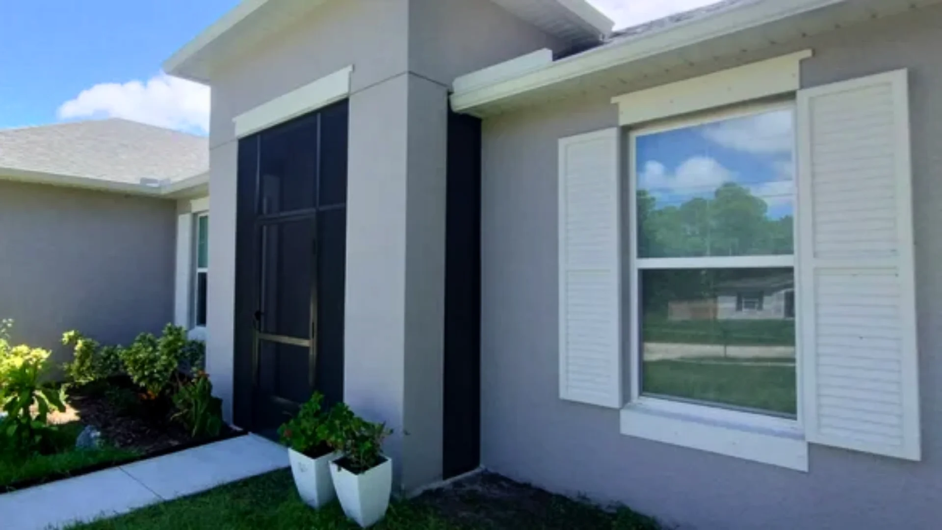 Gray home exterior with white louvered shutters beside a front window Gray home exterior with white louvered shutters beside a front window
