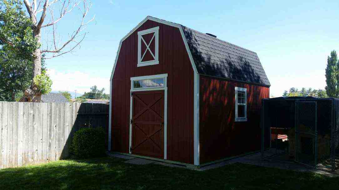 A red barn-style shed with a white trim in a residential backyard. Perfect for storage or workspace.