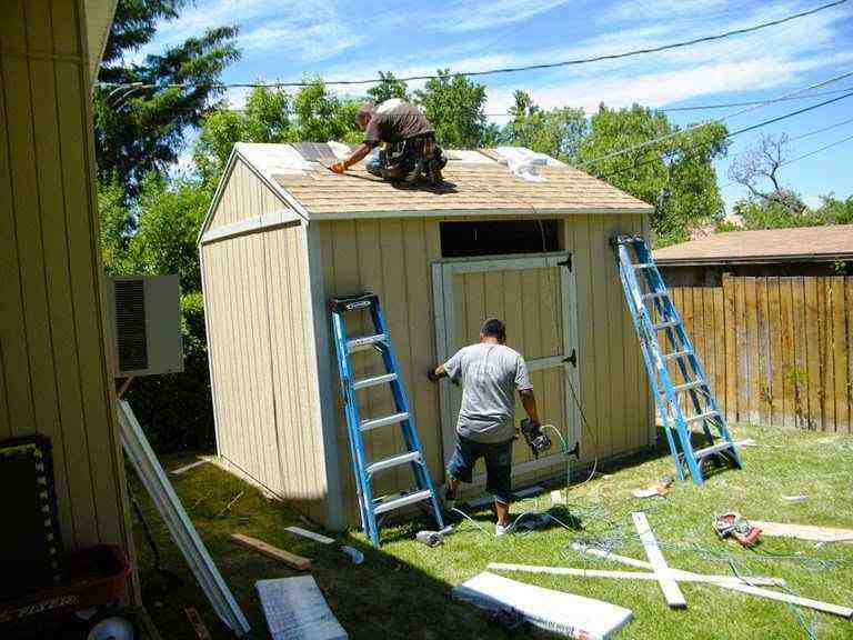 Building a Backyard Shed Step by Step Homeowners installing roof panels and siding on a backyard shed, showing hands-on progress to build your own shed from foundation to finish.