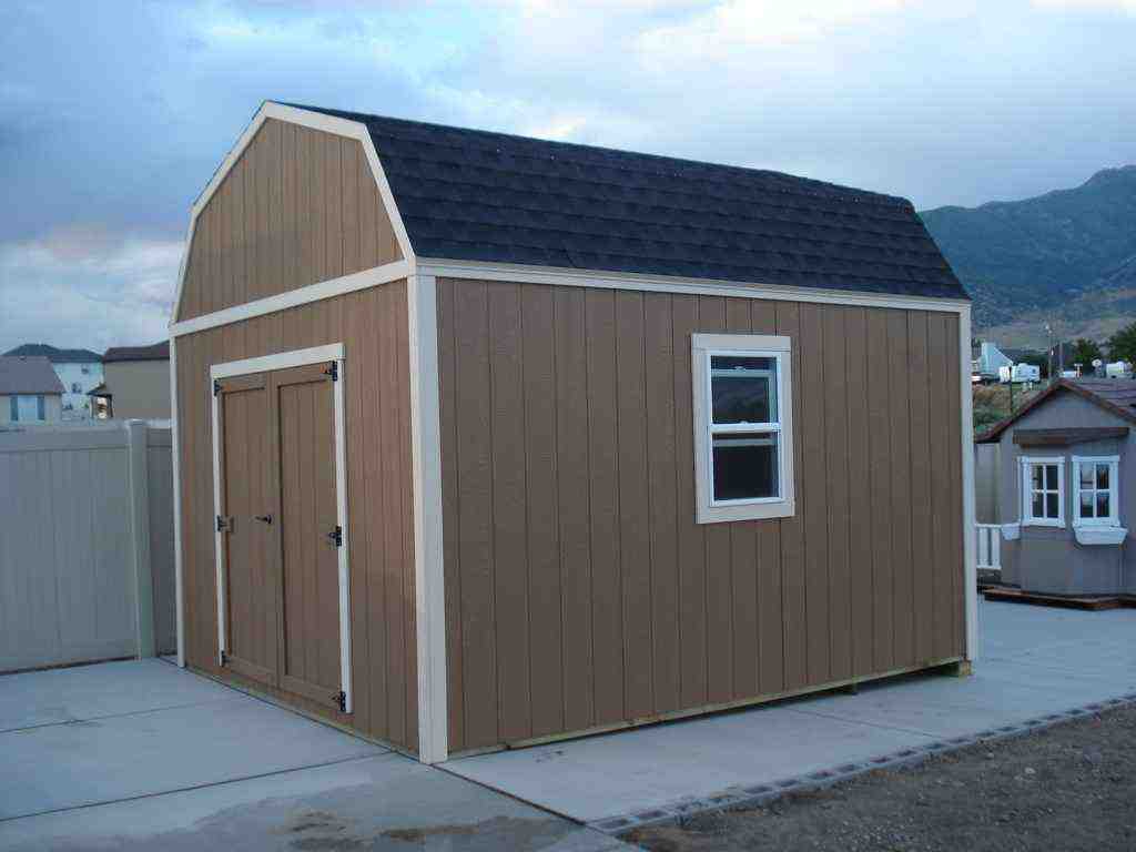 Brown and white double-door farm-style wood shed near me with gambrel roof design, ideal for extra outdoor storage space.