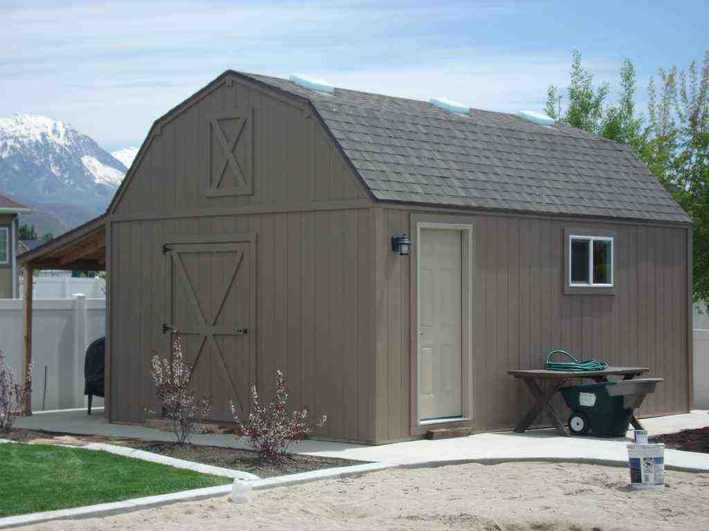 A farm-style shed with a sloped roof, man door, windows, and a scenic mountain backdrop.
