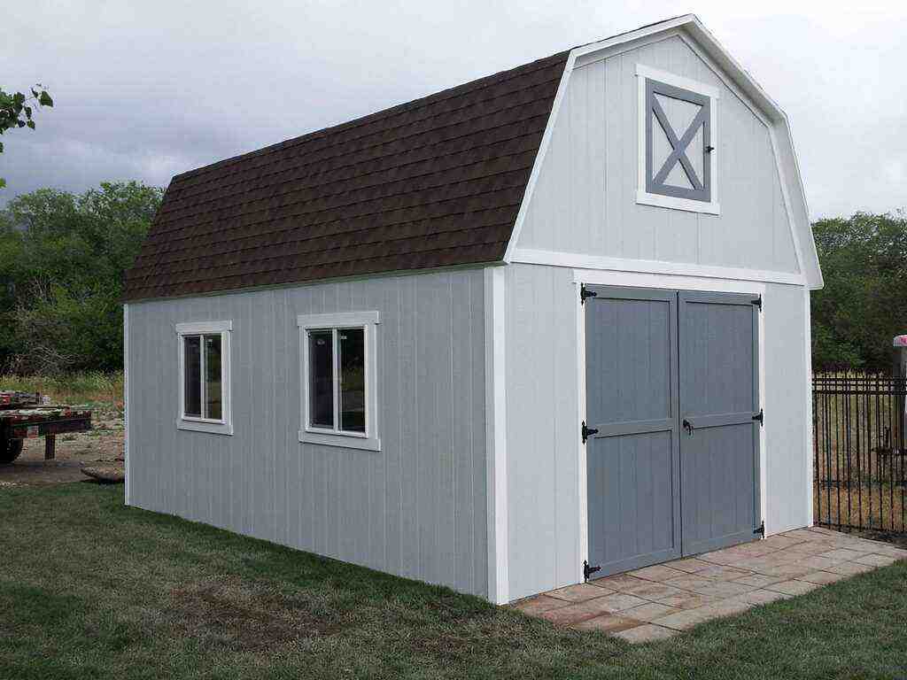 Gray farm-style shed with gambrel barn roof, double doors, and side windows, showing a spacious storage building suitable for farm, workshop, or equipment use