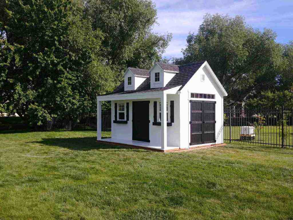Charming orchard shed with black accents, A-frame dormer, and porch, designed to follow Utah shed building code.
