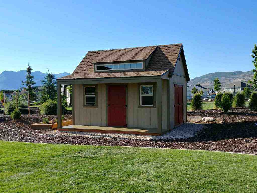 Painted orchard shed with red doors, side porch, and deck for stylish backyard storage solution.