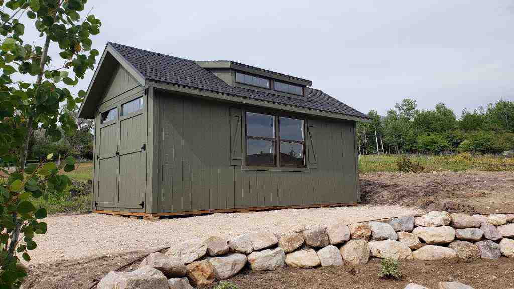 A rustic green custom built storage shed with a spacious overhang, perfect for extra storage and style.