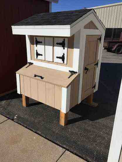 A small tan and white chicken coop with a slanted roof, storage compartment, and multiple shutters.