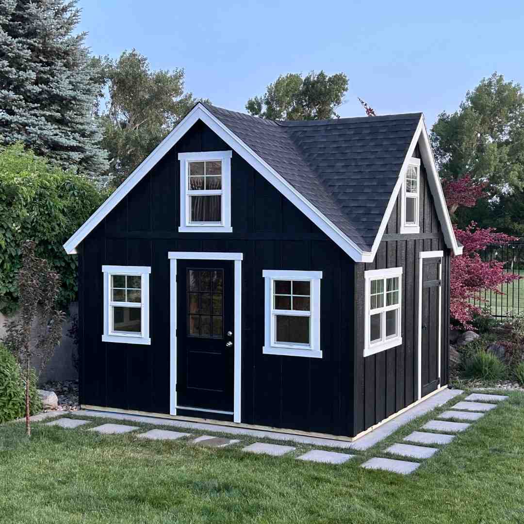 Black Orchard Shed with White Trim Design Black orchard shed with white trim featuring a steep roof, multiple windows, and a clean backyard setup for storage or workspace use.