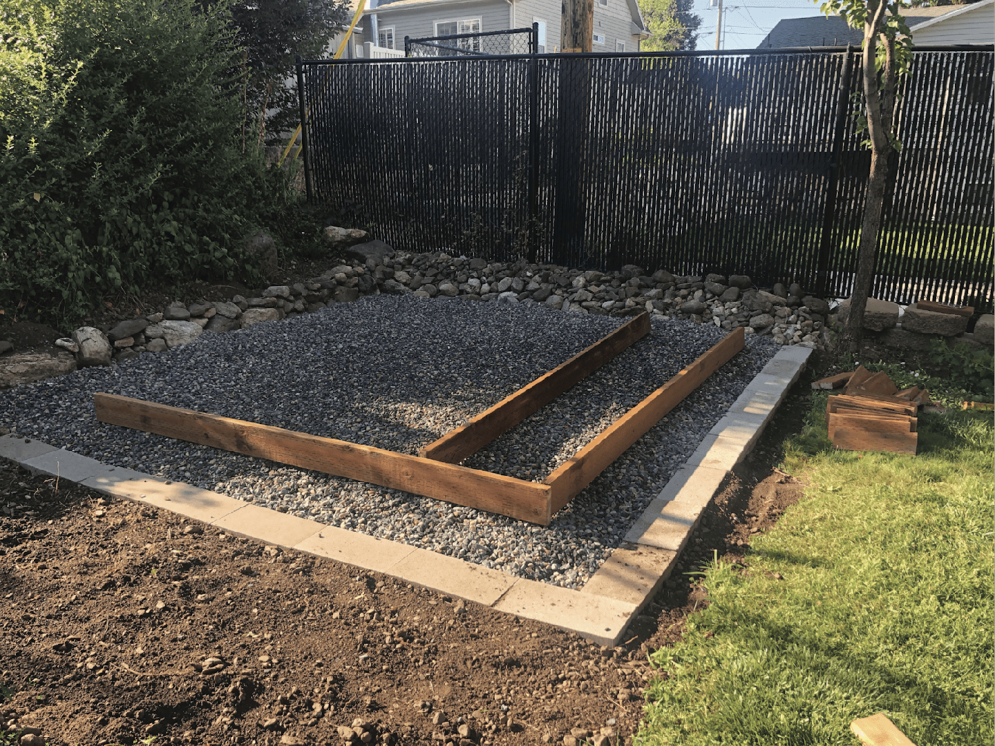 A gravel foundation with wooden framing laid out, preparing the base for a shed build.
