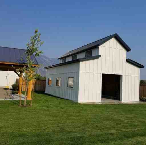 Spacious white pole barn used as a garage, ideal for custom carports and sheds in a large backyard.