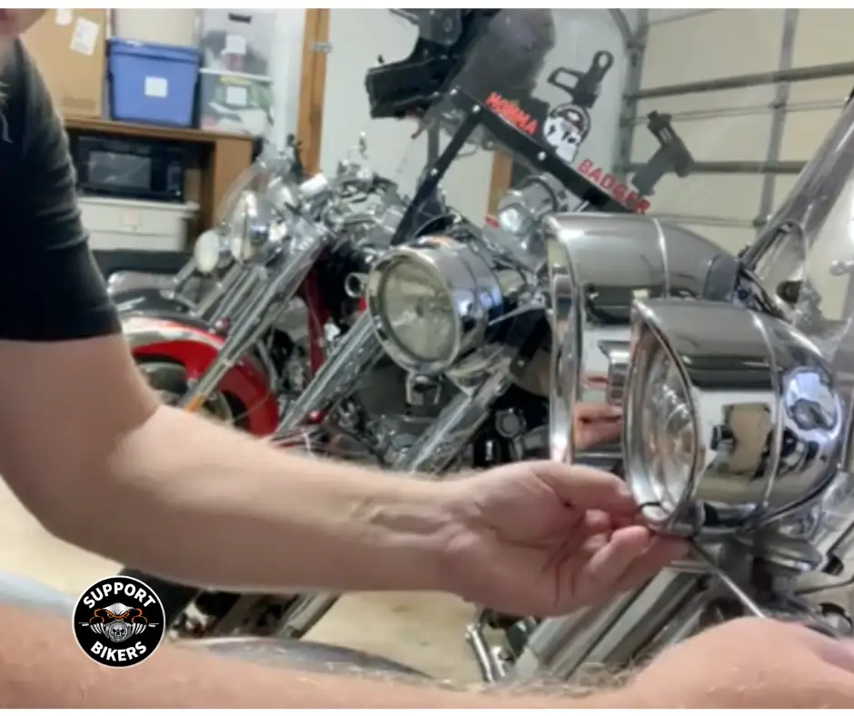 biker installing new bulb next to classic American motorcycle headlight housing - Headlight bulb replacement