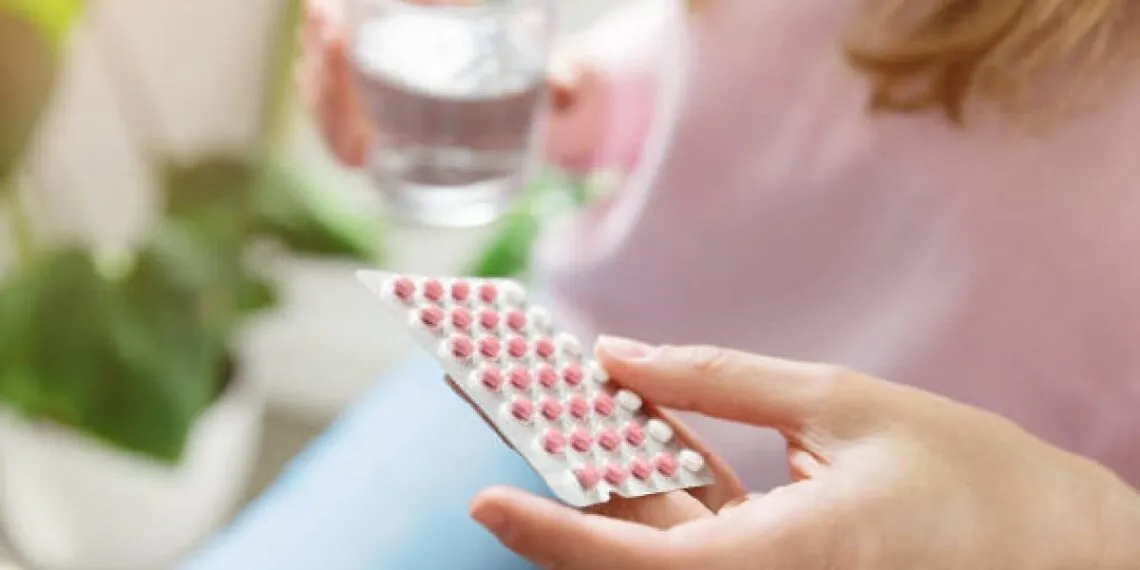 Woman holding a birth control pill pack while learning about contraception and reproductive health.