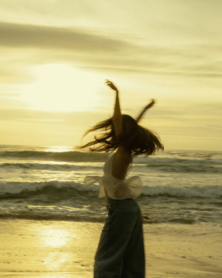 Woman dancing freely at golden hour beach sunset