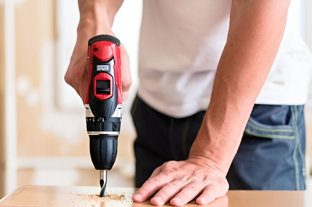 Guy drilling a hole on a desk