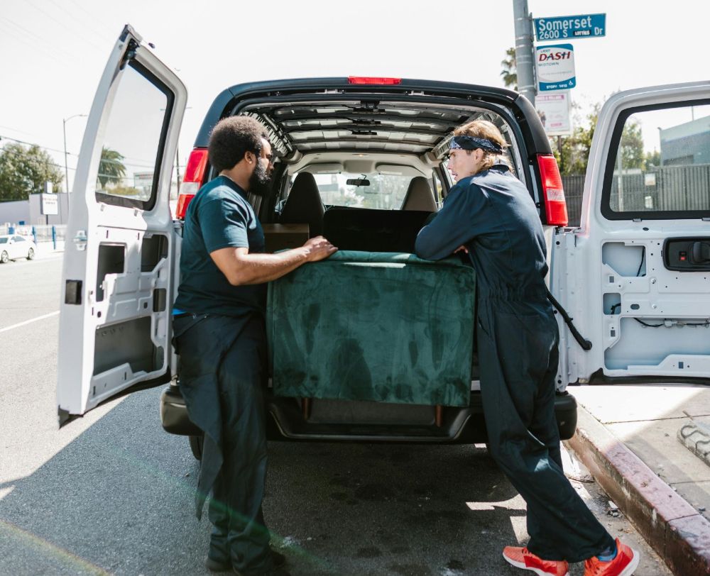 Two movers carrying a couch into a truck