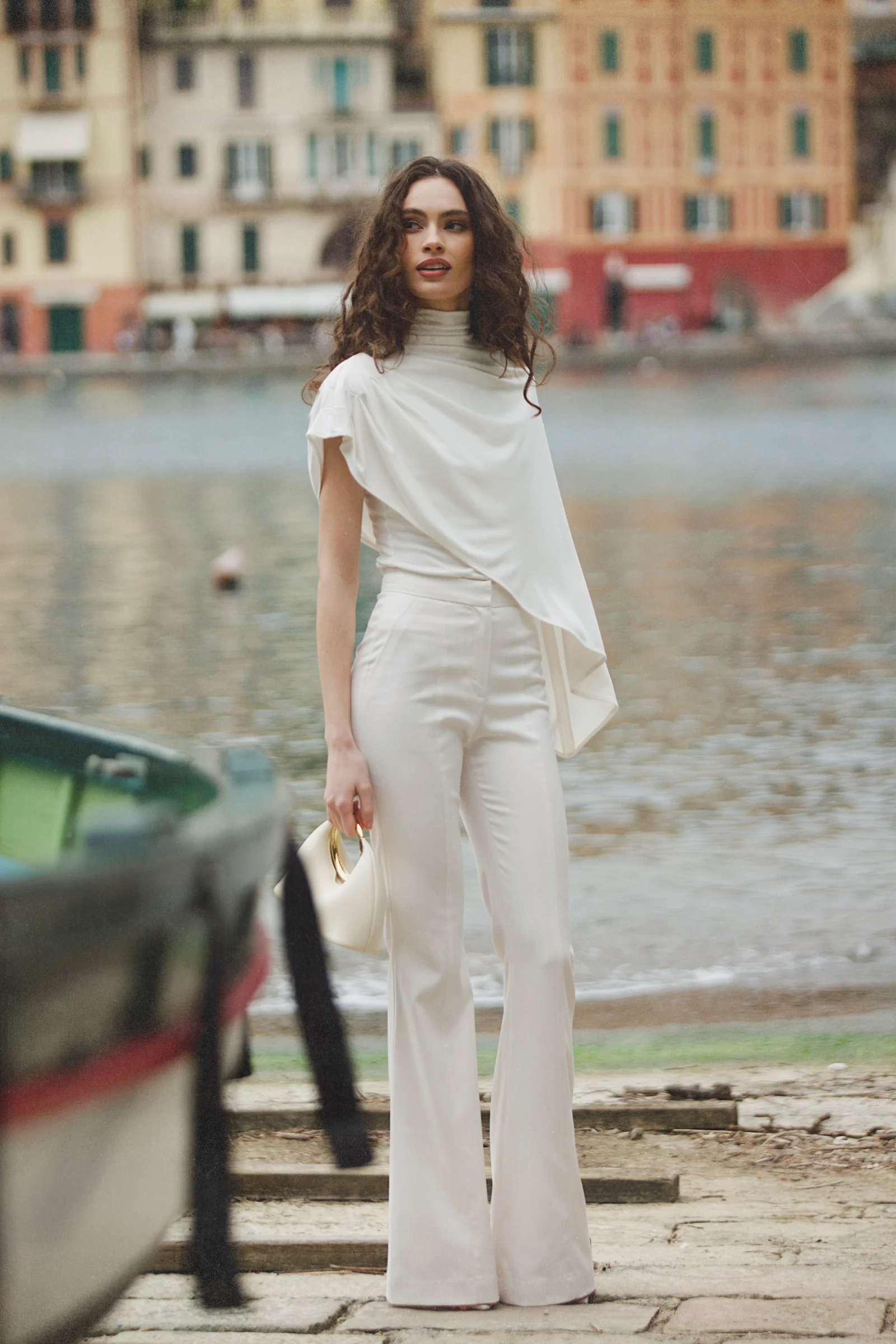 White asymmetric designer top with high neck, integrated cape, and fluid draping 