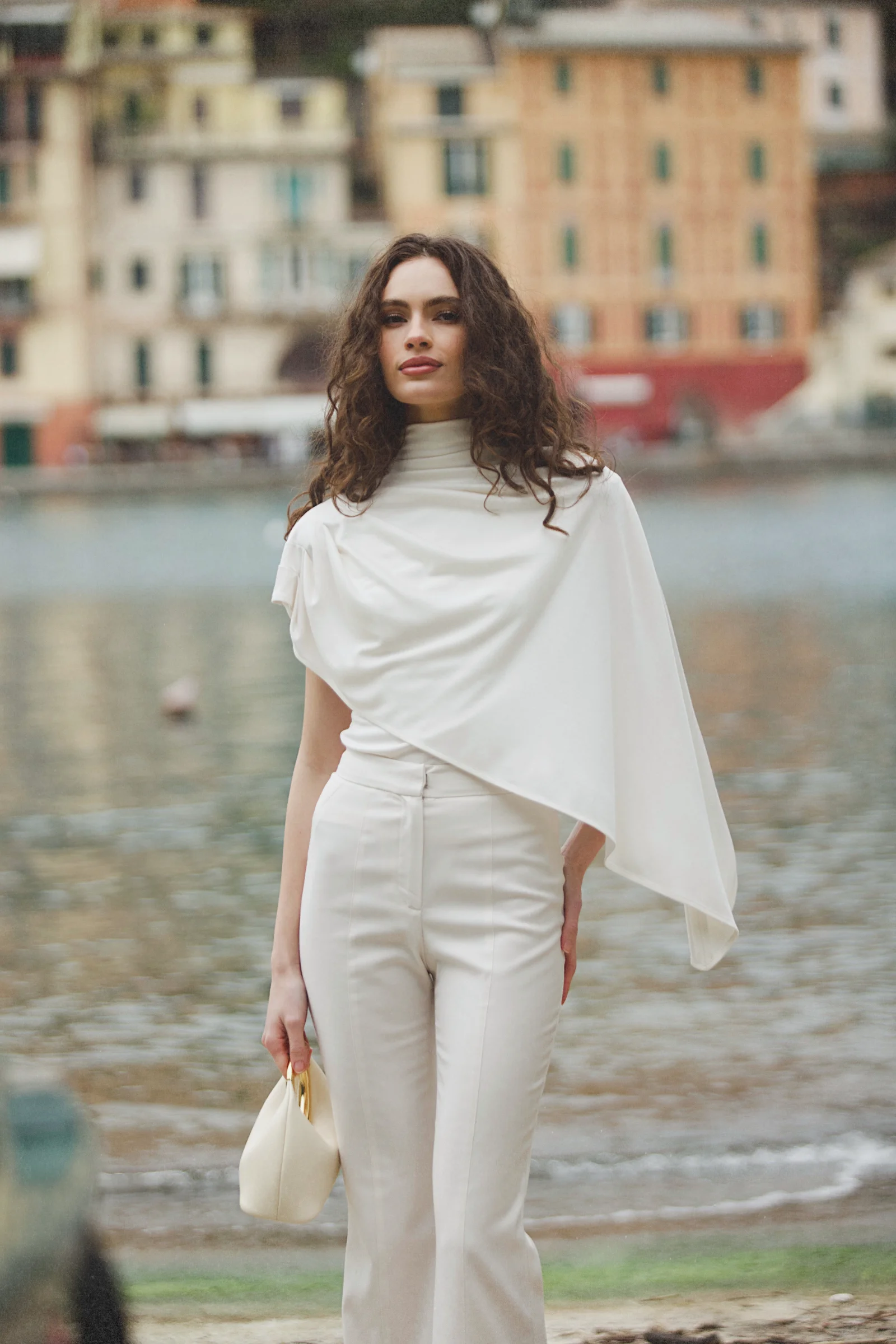 White asymmetric designer top with high neck, integrated cape, and fluid draping 