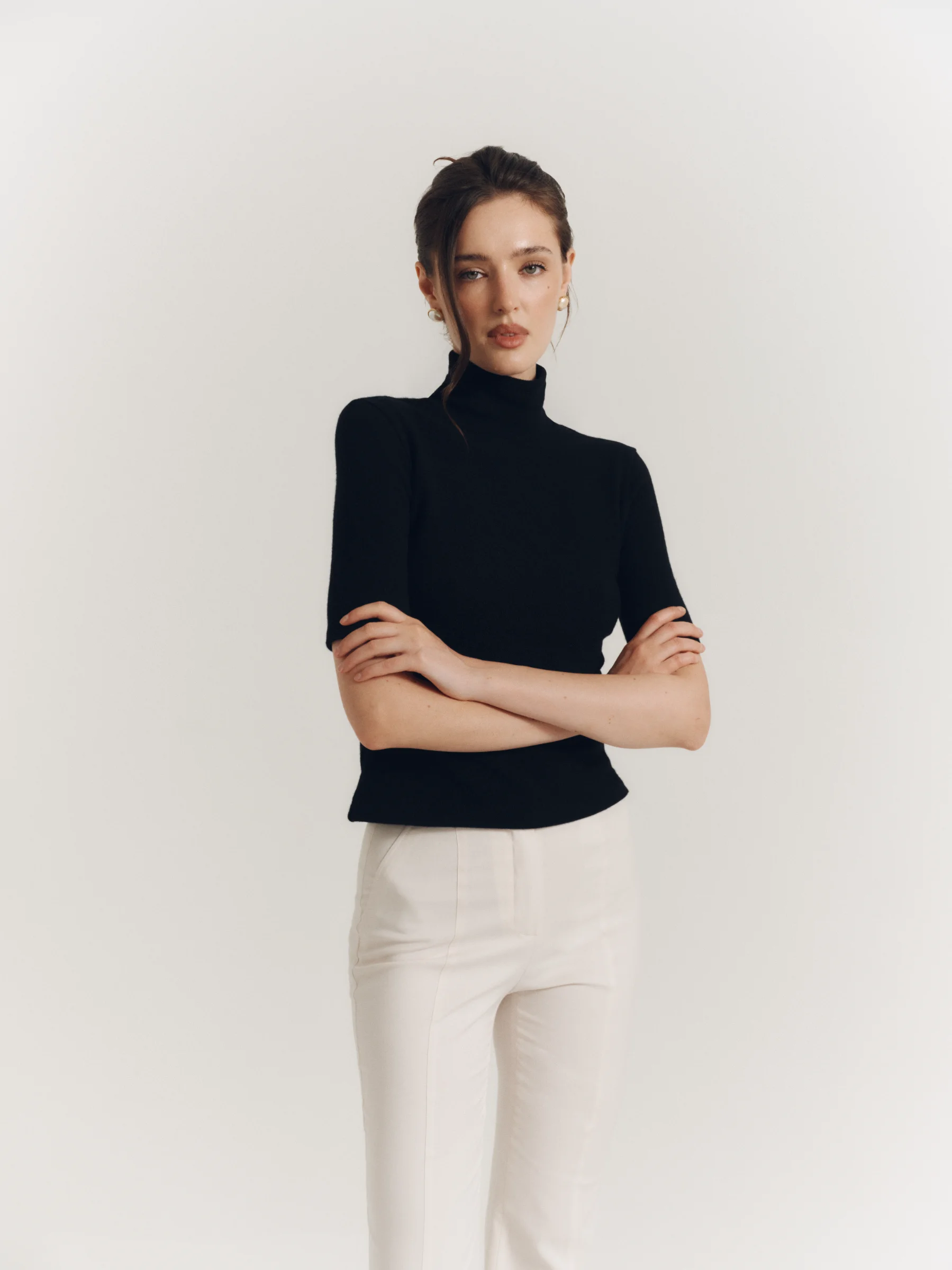 The classic black wool Jet Set top with a high neckline and elbow-length sleeves for women in an old money style 