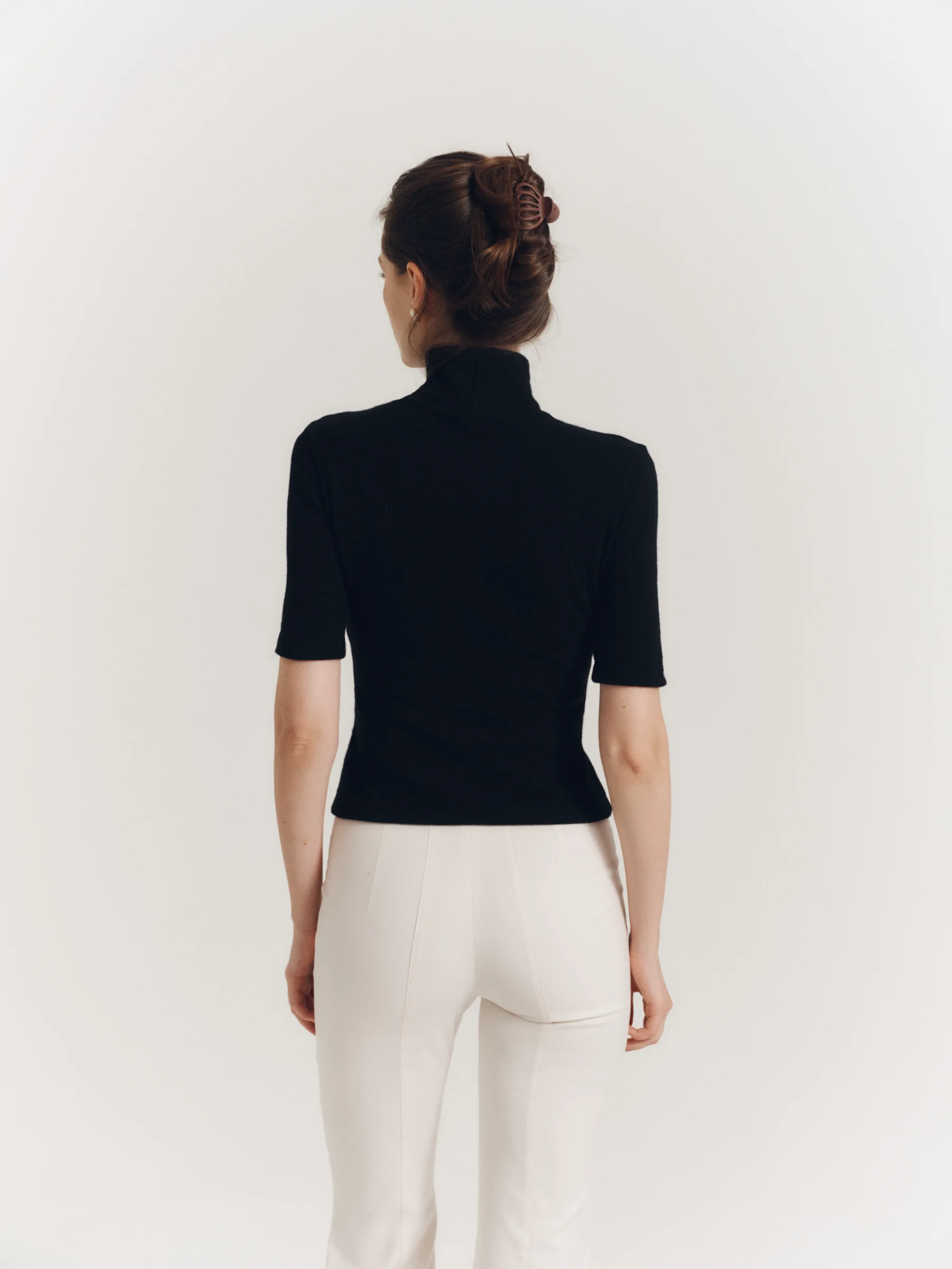 The classic black wool Jet Set top with a high neckline and elbow-length sleeves for women in an old money style 