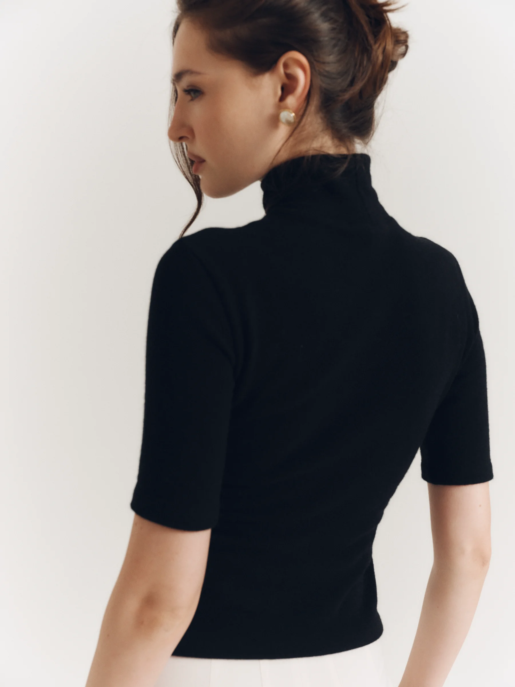 The classic black wool Jet Set top with a high neckline and elbow-length sleeves for women in an old money style 