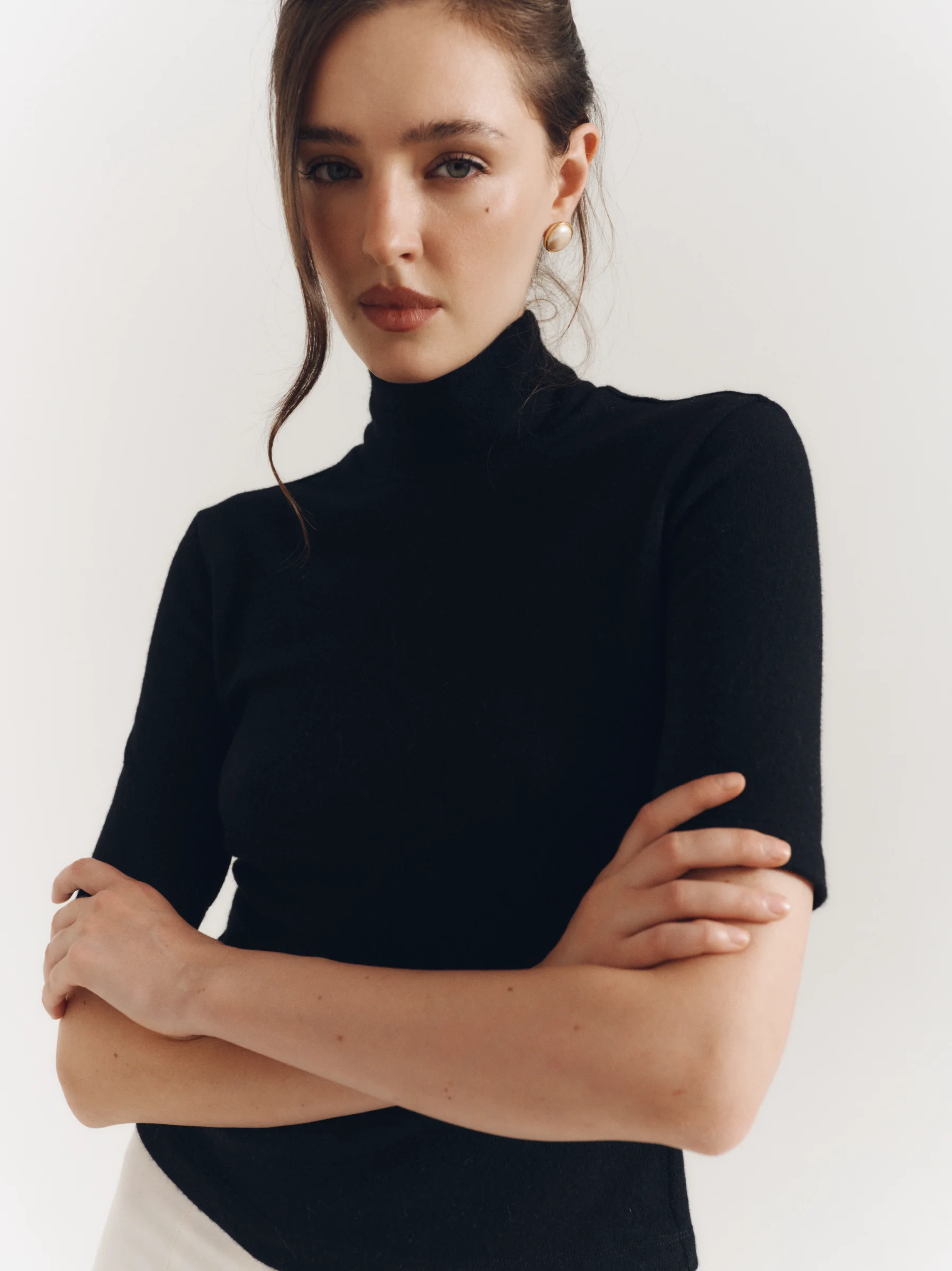 The classic black wool Jet Set top with a high neckline and elbow-length sleeves for women in an old money style 