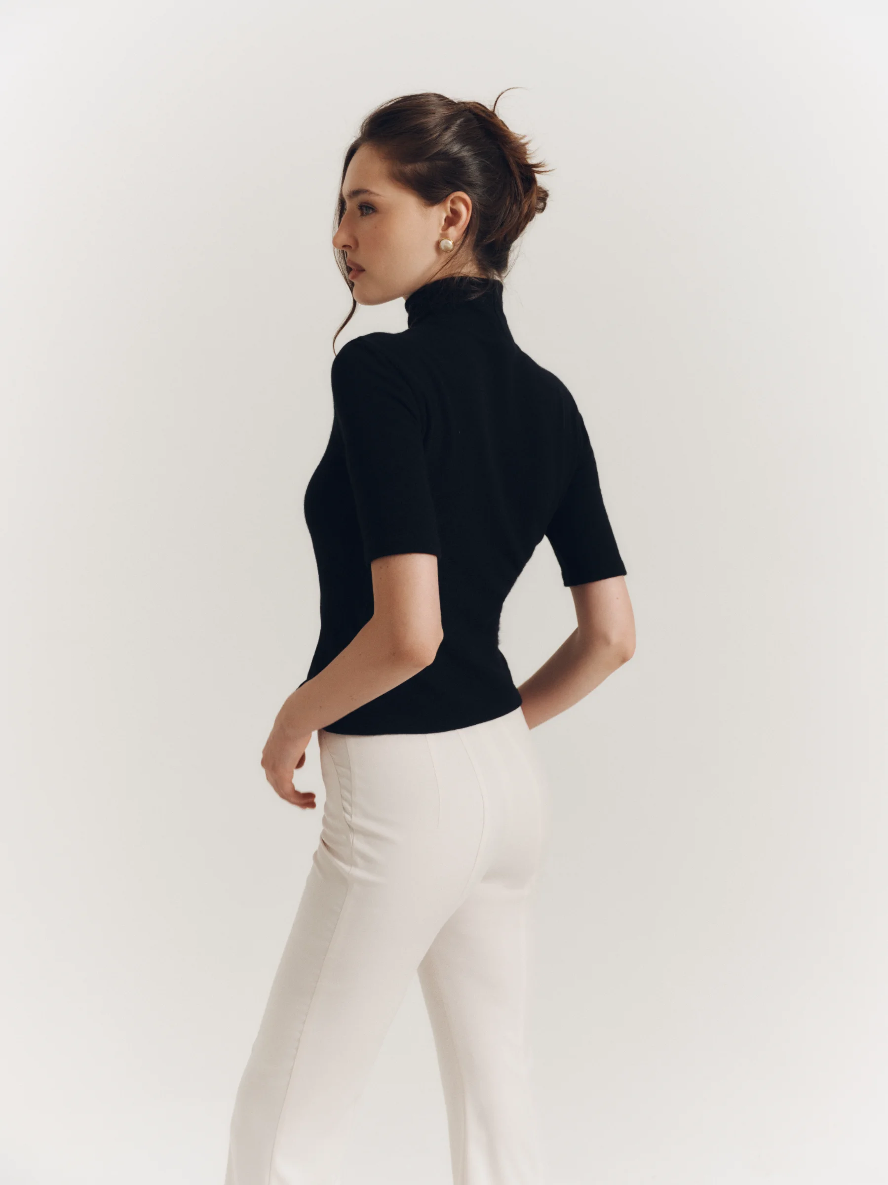 The classic black wool Jet Set top with a high neckline and elbow-length sleeves for women in an old money style 