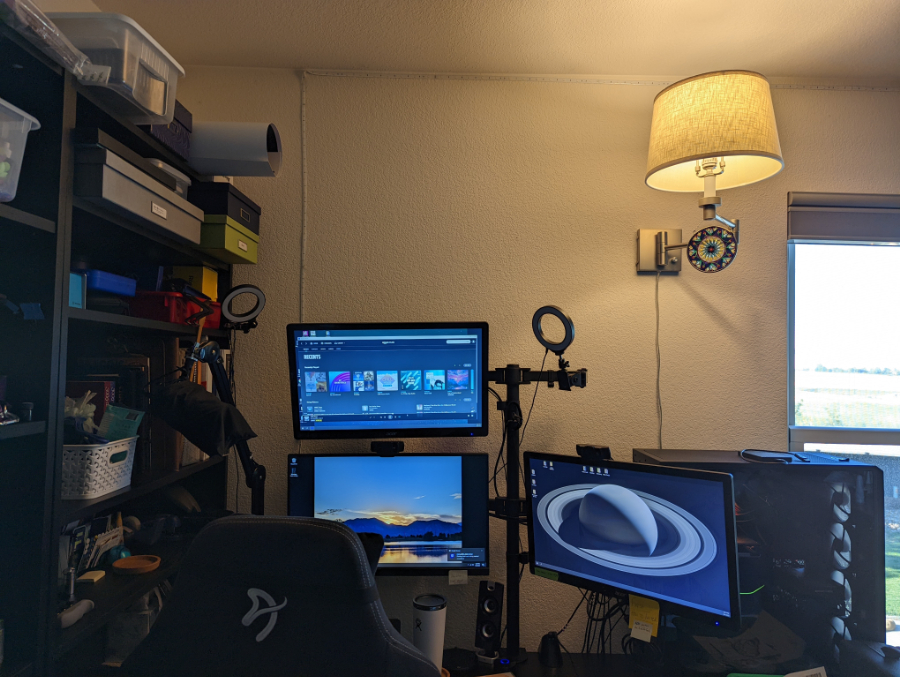 Photo of Shannon's desk showing her chair and her 3-monitor setup. A bookshelf can be seen to the left and her very large PC case is behind the right monitor.