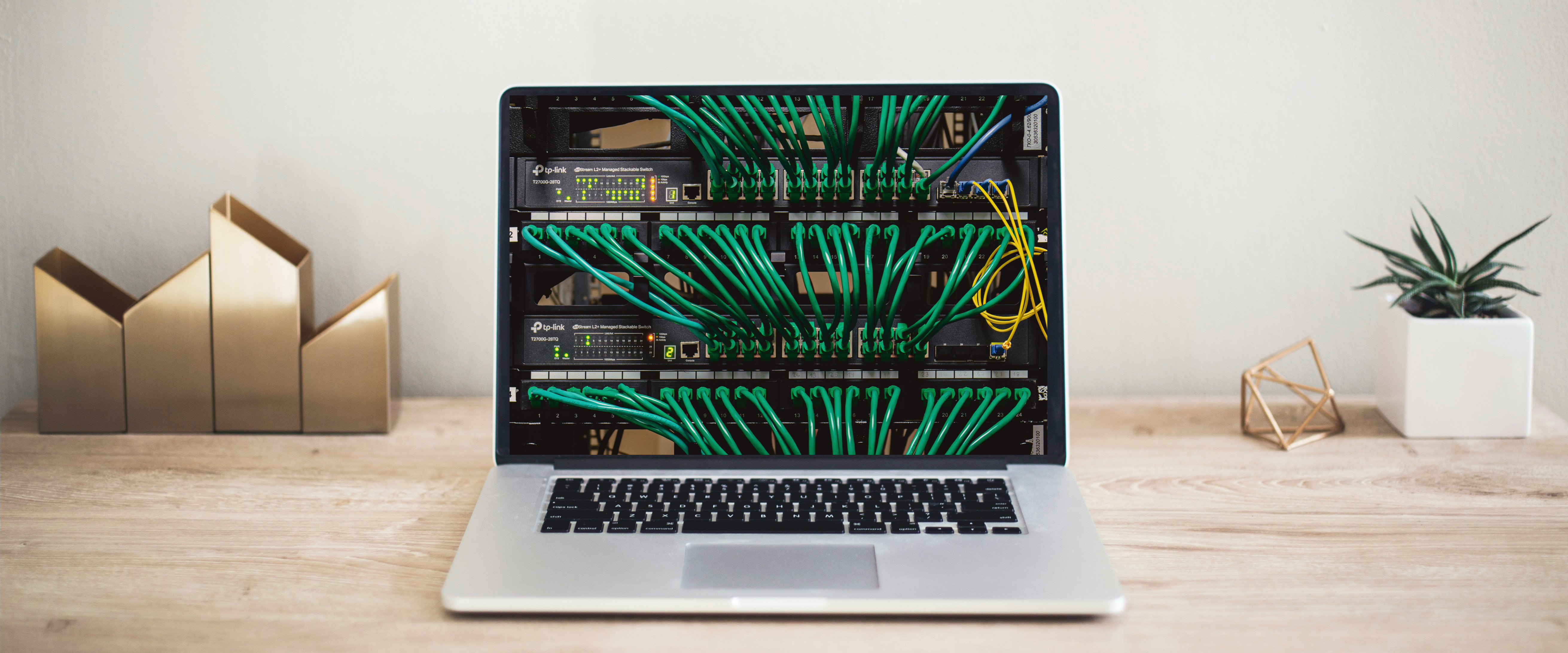 Laptop sitting on a clean wooden desktop showing an image of servers on the screen