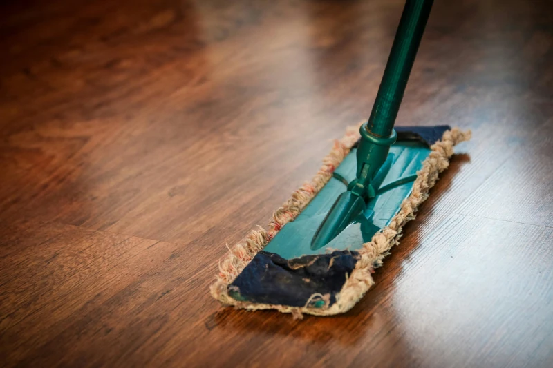 Sweeper with a green handle resting on a wood floor