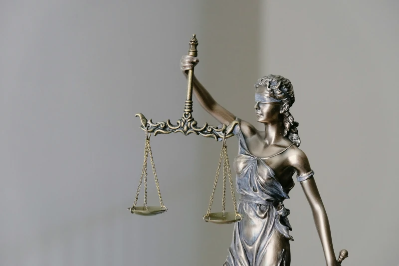 Justice standing blindfolded while holding scales in one hand and a sword in the other.