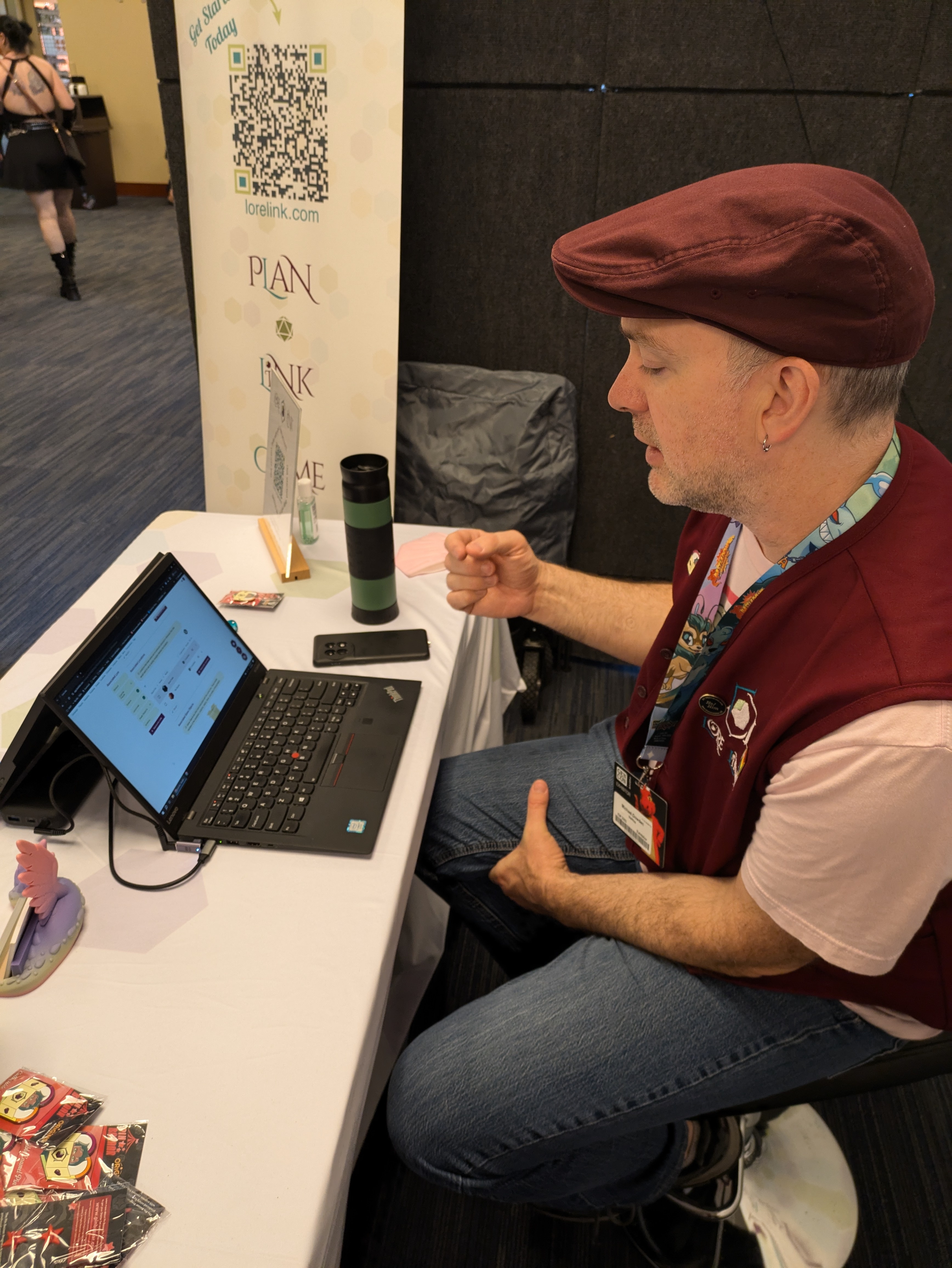 A man sitting down in front of a laptop, looking at a Lore Link screen on the monitor. He's gesturing as he explains how the system works.