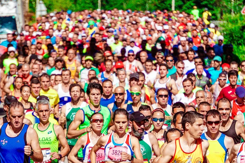 Mass of over 100 runners moving as a pack along a road.