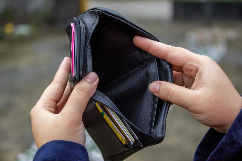 A person is holding their wallet open to show that it has no cash