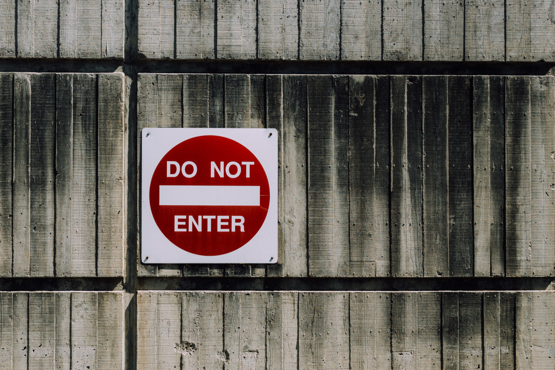 Wooden fence showing a large Do Not Enter sign with a red circle on a square white sign