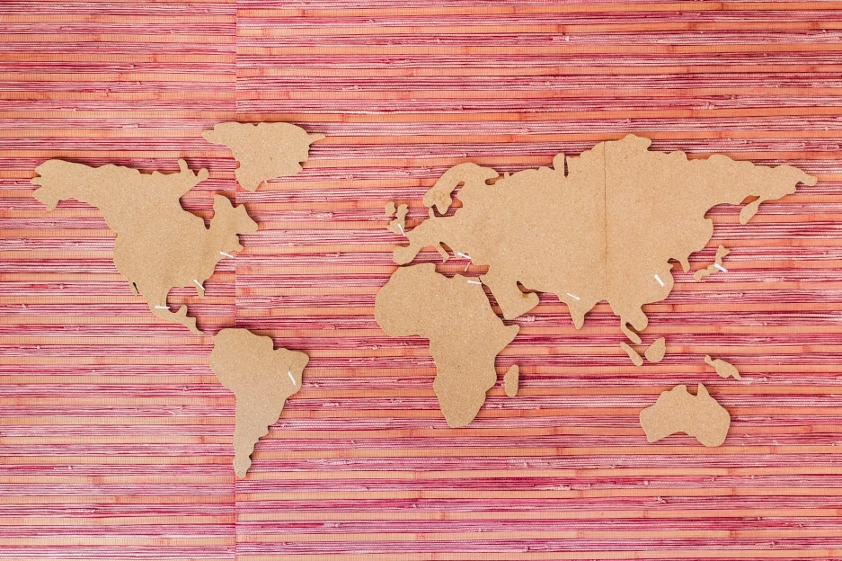 World Map Paper cutout outline of the world map with white paper pins highlighting key regions.