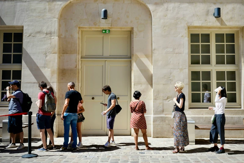 People waiting in line in front of a stone building