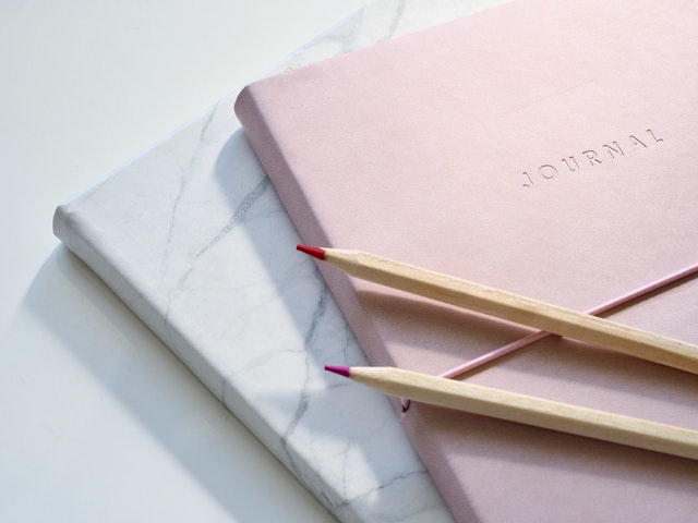 white marbe journal and pink journal with pens