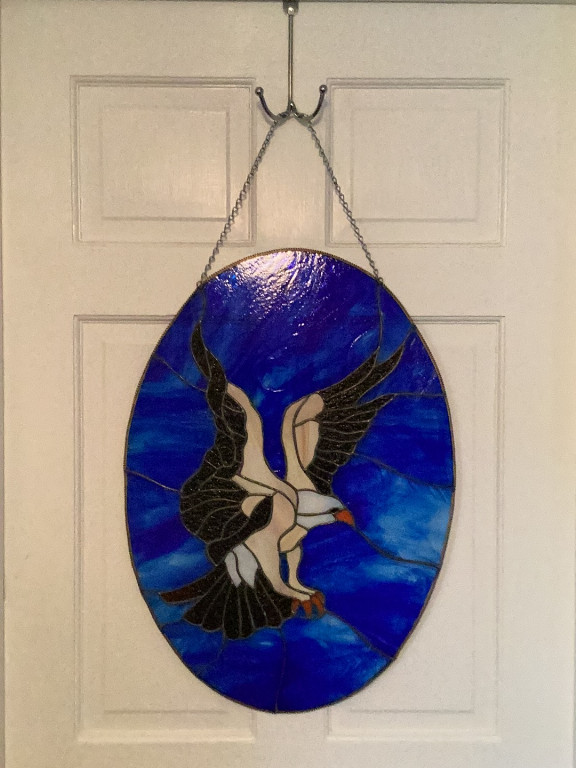 Stained glass sun catcher featuring an American Bald Eagle in flight against a blue background