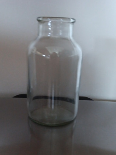 Clear glass bottle, likely a vintage milk bottle or pharmaceutical vial
