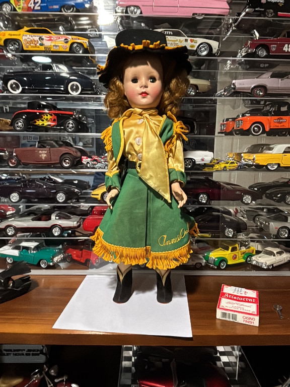 Hard plastic doll in cowgirl outfit with 'Annie Oakley' embroidered on skirt, circa 1950s-1960s