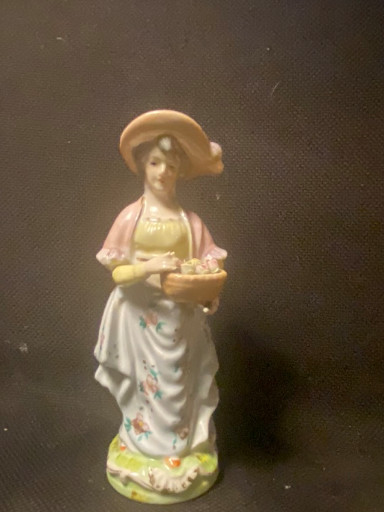 Porseleinen beeldje van een vrouw met hoed en bloemenmand