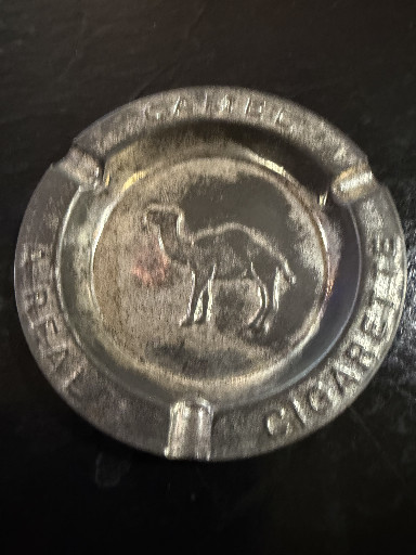 Metal advertising ashtray for Camel Cigarettes featuring embossed camel logo