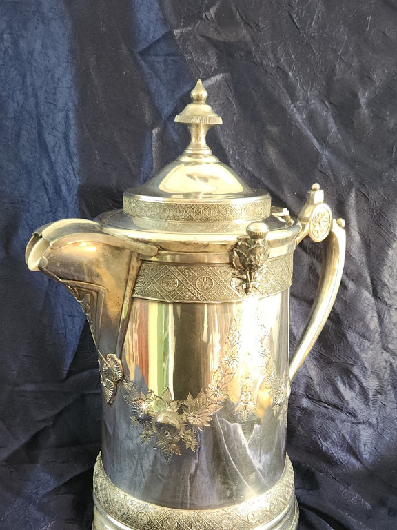 Five piece silver-plated water pitcher. Two thumb screws holding finial, spout cover and lid lip in place. Removable porcelain insert. Patented by Reed & Barton on August 4 1868 and on May 18 1878. Recently sold without porcelain insert for $275.