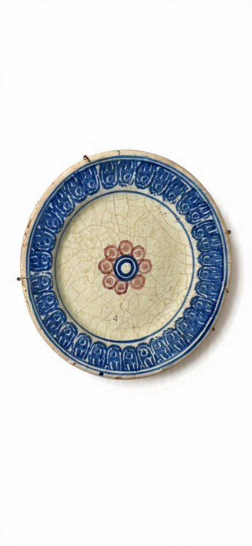 Piatto in ceramica smaltata con decorazione floreale centrale e bordo blu con motivi ripetuti