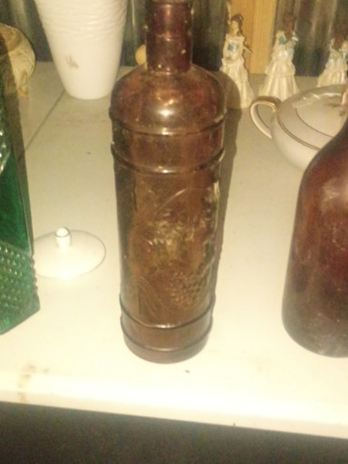 Amber glass bottle with embossed decorative pattern