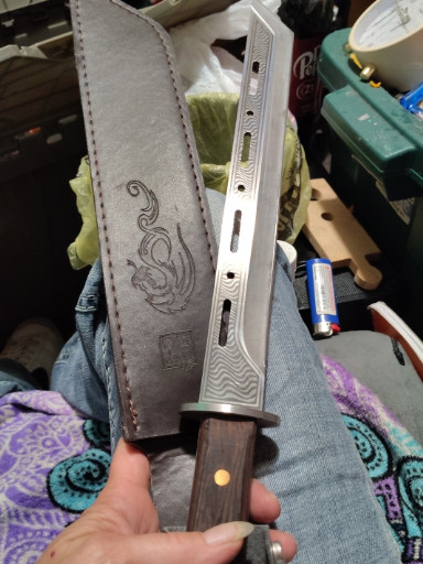 Decorative fixed-blade knife with leather sheath featuring dragon embossing