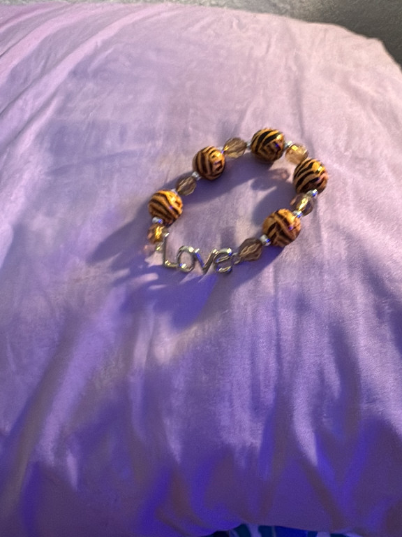 Beaded stretch bracelet with tiger stripe pattern beads and 'love' charm