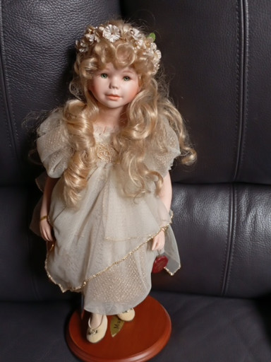 Porseleinen decoratieve pop met blond krullend haar en ivoren jurk