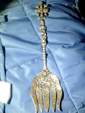 Gold-tone metal serving fork with ornate Baroque-style floral and cherub decoration by Ugo Bellini