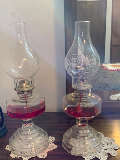 Pair of glass oil lamps with cranberry-colored font bases and clear glass chimneys